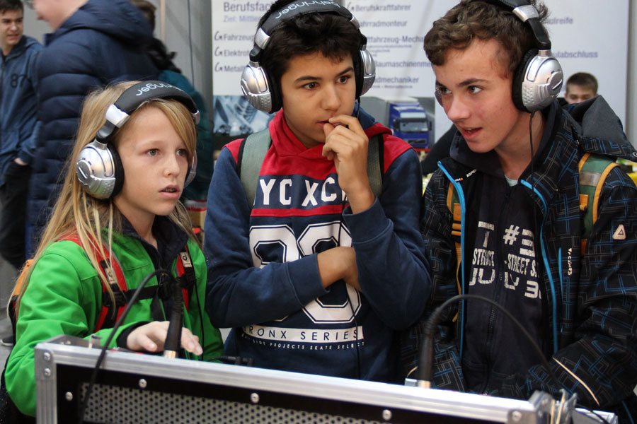 Kinder mit Kopfhörern konzentriert an einem Gerät/ Children with headphones concentrated on one device